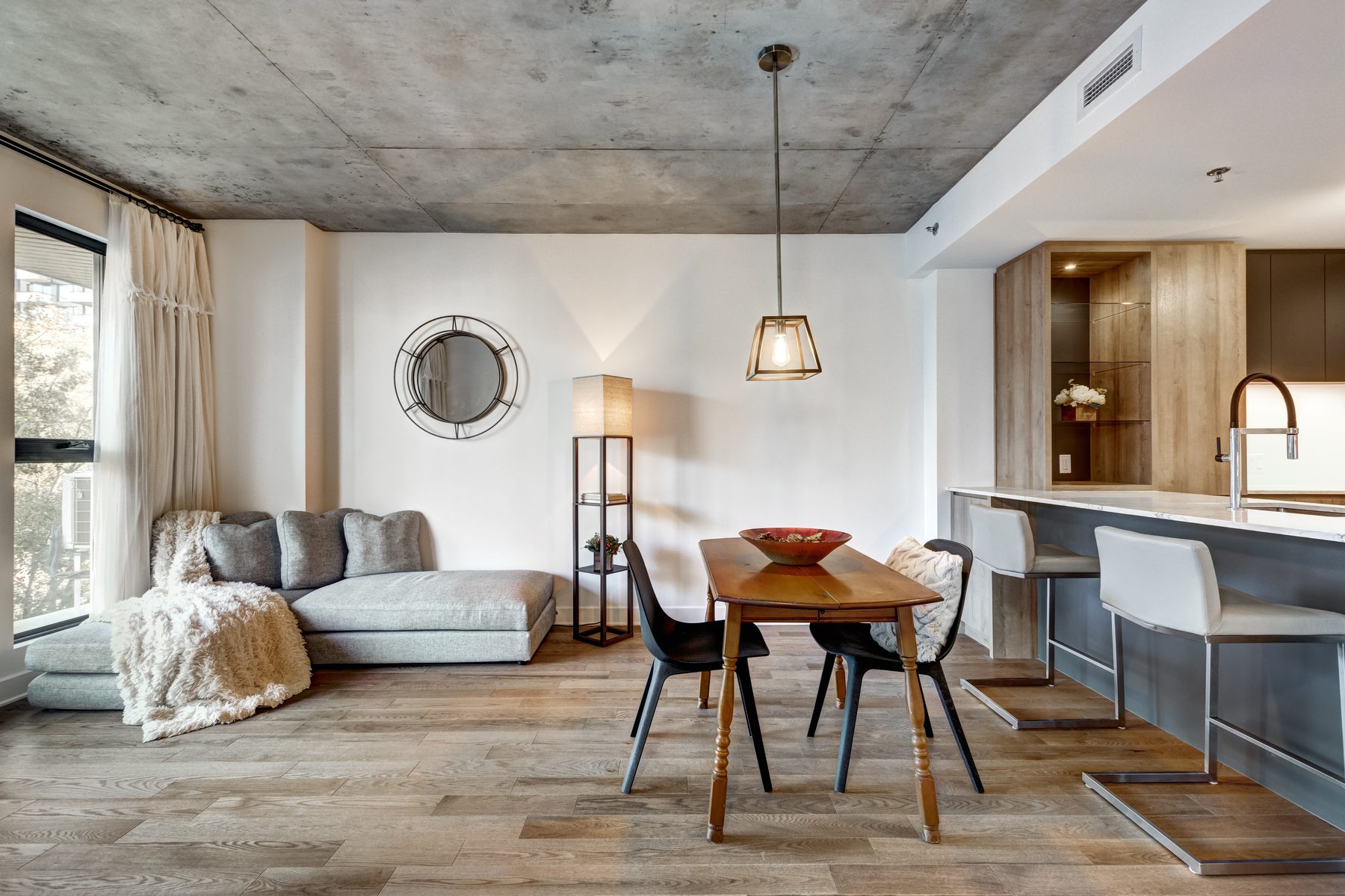 Furnished apartment dining area and kitchen with pendant light and round mirror