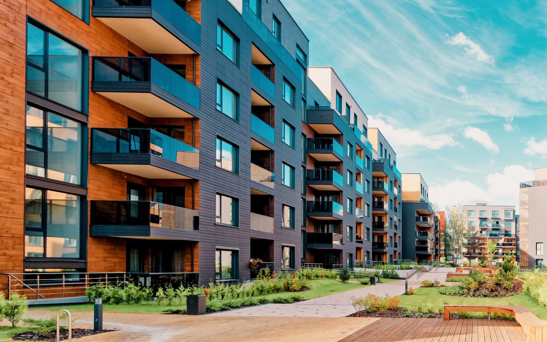 Newly built multi-family apartment buildings with balconies under a blue sky
