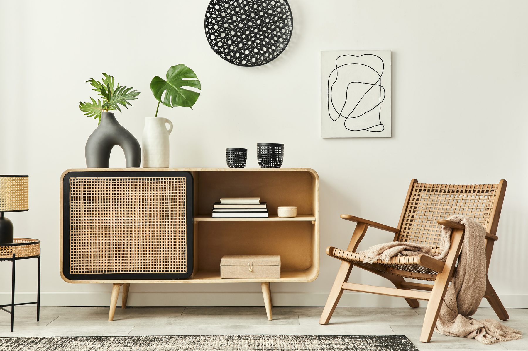 Bright living room with rattan sideboard, woven armchair and houseplants